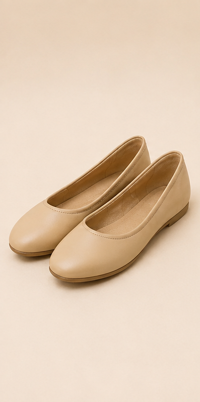 A pair of beige leather ballet flats with a rounded toe and low flat heel, displayed on a solid beige background.

